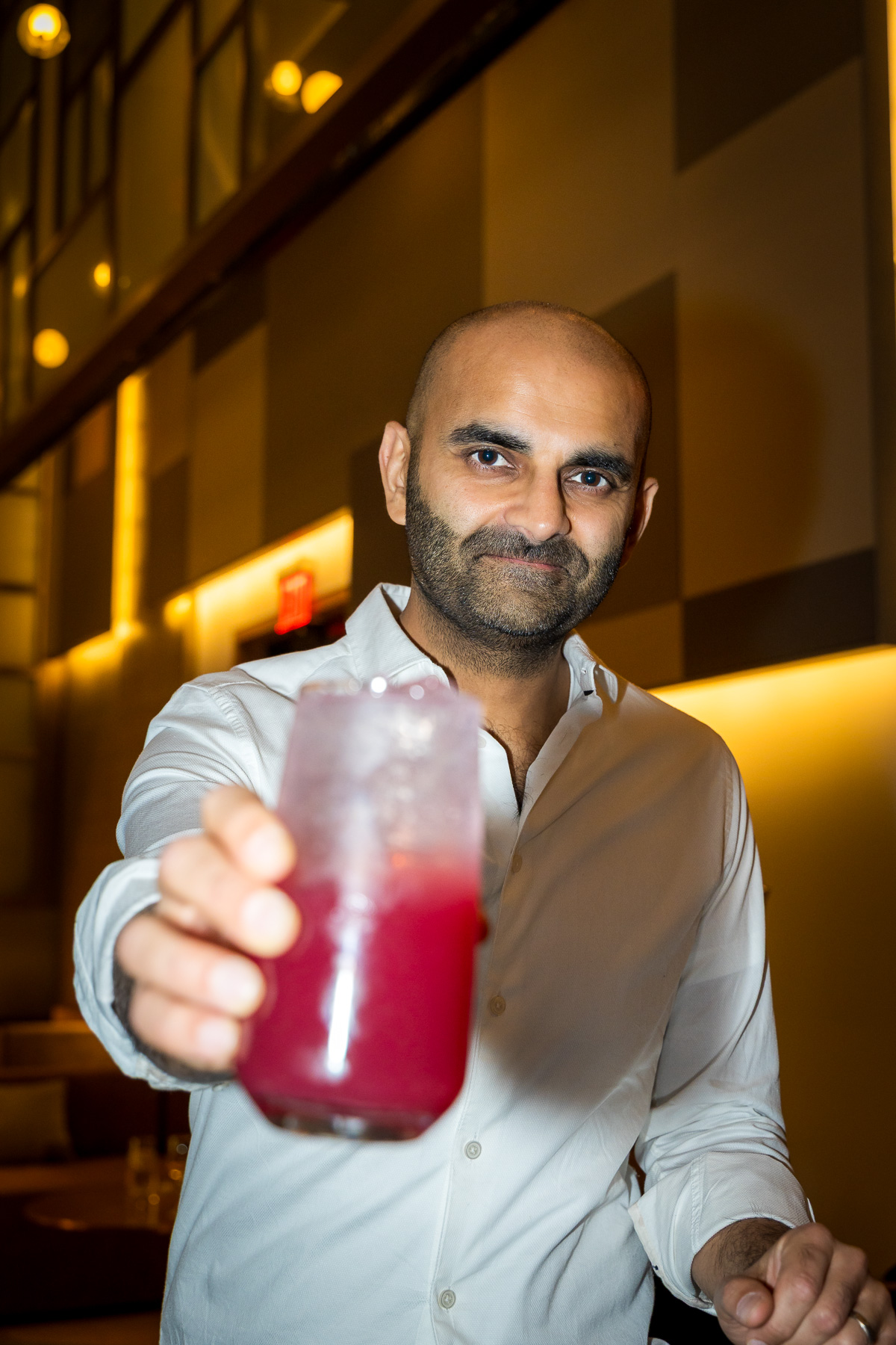 Close-up of guest toasting at a birthday event, smiling directly at the lens.